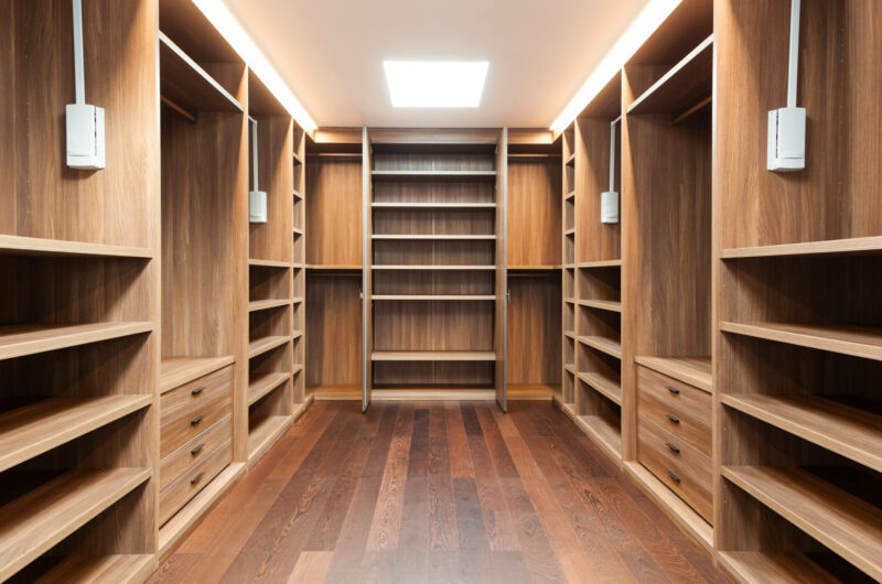 Drewniana zabudowa garderoby, podzielona na szafy półki i szuflady
